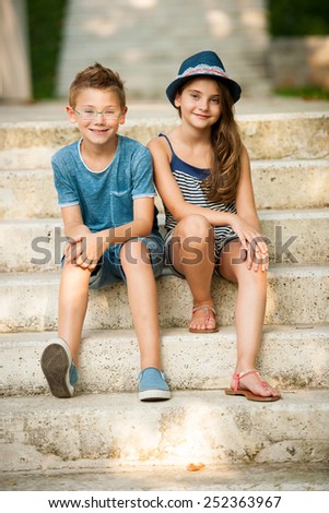 Teenage boy and girl sitting on stairs in park on summer afternoon