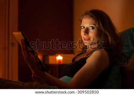 Pretty woman surfing web on a tablet in bed before sleeping