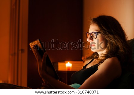 Pretty woman surfing web on a tablet in bed before sleeping