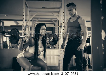 Personal fitness coach trains beautiful woman in gym