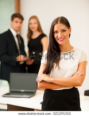 Business woman - secretary  standing in first plain with coworkers in background  Young boss entrepreneur