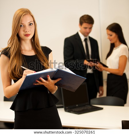 Business woman - secretary  standing in first plain with coworkers in background  Young boss entrepreneur