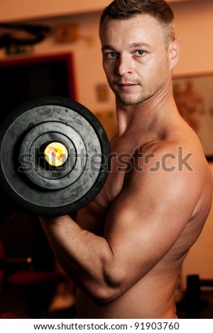 Man exercising his arm muscles by lifting two dumbell free weights in a fitness club.