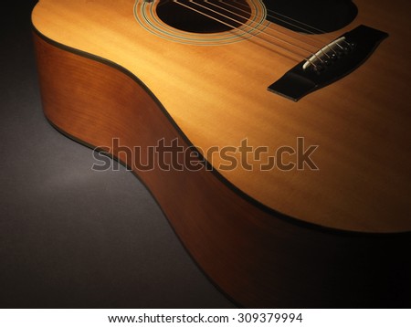 Close up shot of an acoustic guitar body with graduated lighting to allow for darkened copy space for the designer.