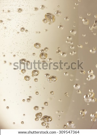 Close up, full frame shot of champagne bubbles in a glass with a shallow depth of field. Please note some bubbles may look like sensor spots as they are more distant and out of focus.