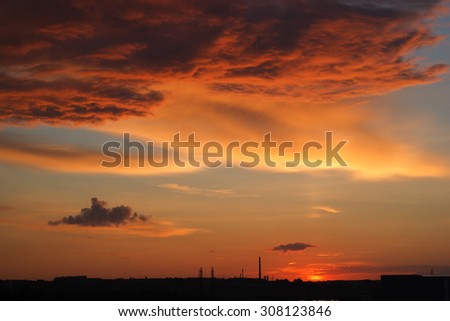 Red storm clouds at sunset. Silhouette of buildings on the horizon.