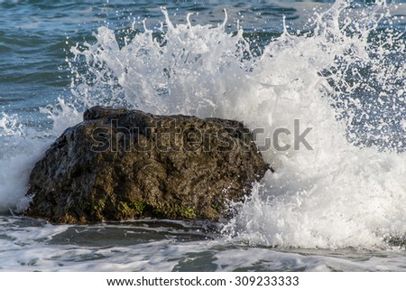 waves hitting a rock form sparkling spray foam