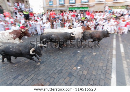 PAMPLONA, SPAIN - JULY 12: People run from bulls on street during San Fermin festival in Pamplona, Spain on July 12, 2015