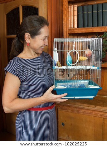 woman with a pet in a cage. Blue wavy parrot.