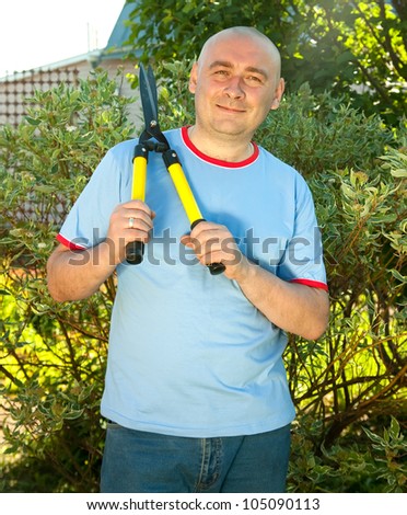 Mature man with garden pruner near   bush