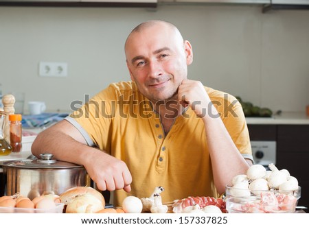 Cheerful man in orange t-shirt in the kitchen