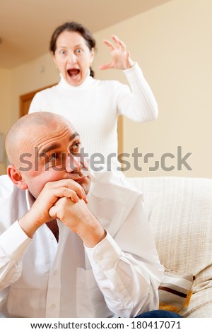 Family quarrel. Sad guy and woman during conflict in living room at home