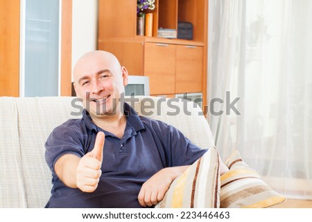 Relaxed man with thumbs up sitting on couch