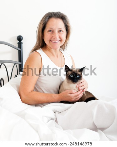 Beautiful older woman with   cat  on   bed.