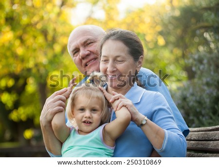 Portrait of grandma and  grandpa with little grandaughter  outdoor