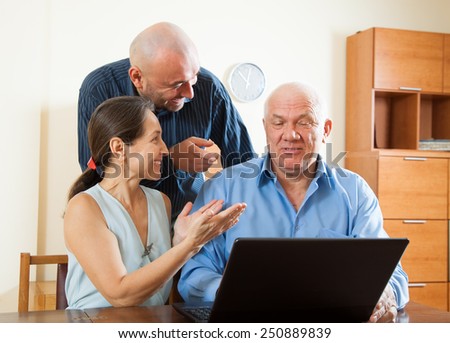 Smiling advisor  standing near mature couple with laptop