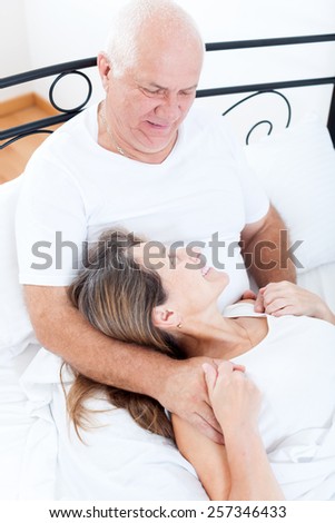 Mature man and woman on   bed in   bedroom.