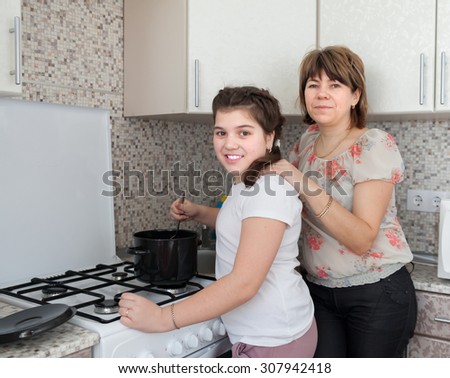 Mom and daughter in   kitchen preparing soup