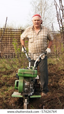 Senior gardener  working in the yard with mini tractor