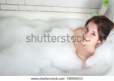 The brunette girl washes in a bath
