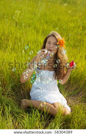 Girl in white dress making soap bubbles during summer