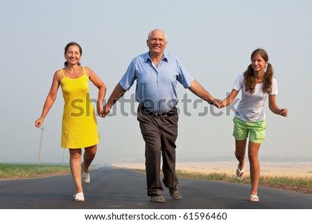 Happy family of three run over a  road at summer