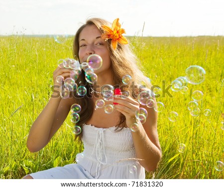 Girl in white dress making soap bubbles during summer