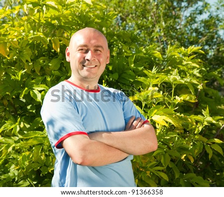 Portrait of a smiling mature guy with arms crossed standing outdoors