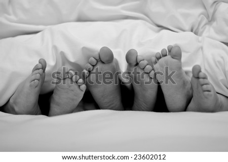 Three pairs of kids feet sticking out of bed