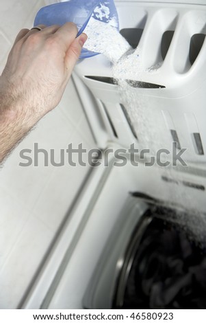 Hand pouring washing powder into washing machine