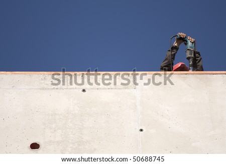 Construction site - worker drilling into concrete wall