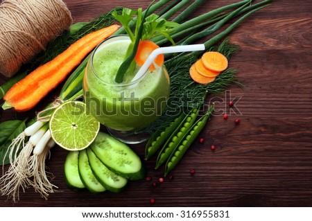 Green smoothies next to the fresh young vegetables; the substrate for the menu bars and restaurants; organic food; drink hipsters; green onion; baby carrots; young peas; lime; green onion