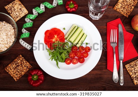 Tomatoes, cucumbers, sweet peppers and arugula on a white plate; concept of healthy food; weight loss; quick reset of the weight; fitness food; organic food