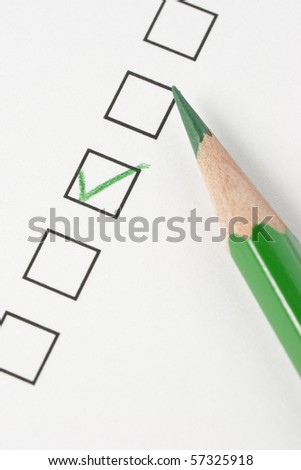 Survey with green pencil and check mark. Focus on pencil tip.