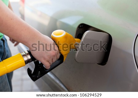 Driver pumping gasoline at the gas station, closeup