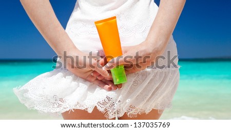 Portrait of woman holding sunscreen cream on beach, beauty concept