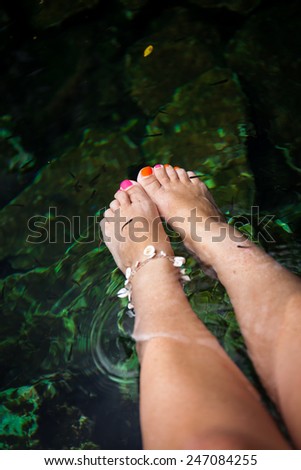 Fish spa therapy with female legs in mexican cenotes