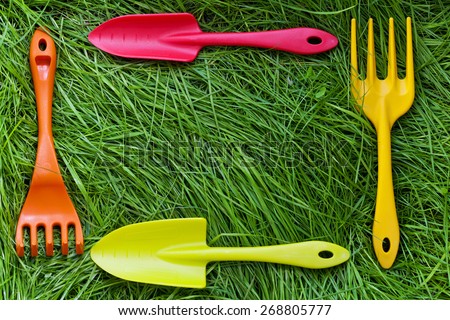 Set of gardening tools on green grass background. Plastic mini shovels, forks and spade.