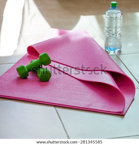 Two dumbbells with mineral water on yoga mat, healthy lifestyle concept