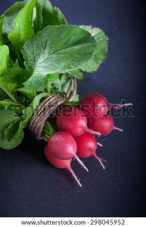 Bunch of ripe red radish on black background, selective focus and shallow depth