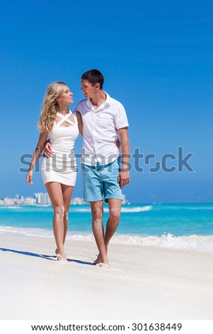 Romantic couple walking on perfect beach with turquoise sea, enjoying life and each other at honeymoon vacation.