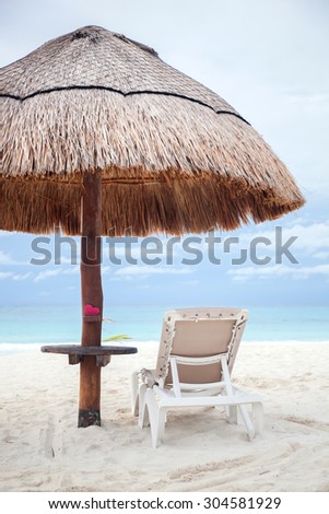 Pink heart object under grass umbrella on tropical beach with copyspace. Travel concept