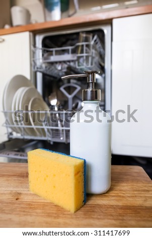 Dishwasher sponge with soap in dispenser tube on background of opened dishwasher machine after cleaning process. Technology timesaving concept.