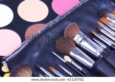 Make-up brushes in leather case on eyeshadows palettes, closed-up
