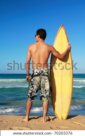 Surfer holding a surf board on beach