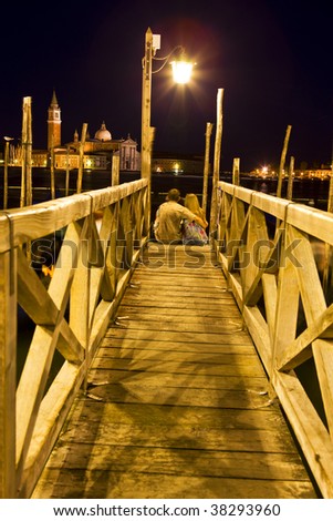two loved young people in the bridge of romantic night in Venice