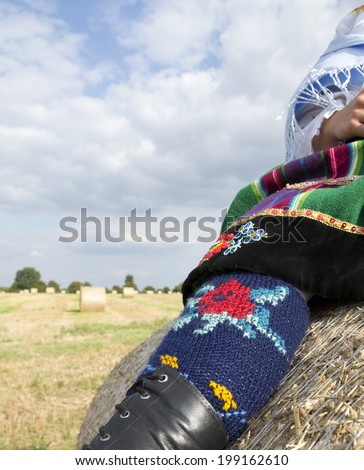 A national and traditional Polish skirt and leg warmers with a folk emblem in the field of harvest straw bales