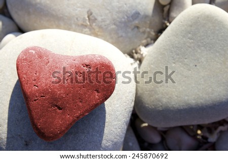 Red stone heart among river or sea pebble stones, Valentine\'s Day, perfect love
