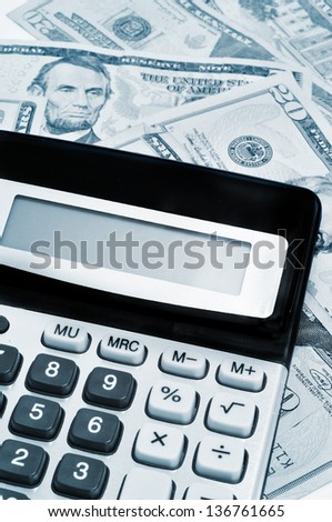 an electronic calculator on a pile of dollar bills, under business and finance concept
