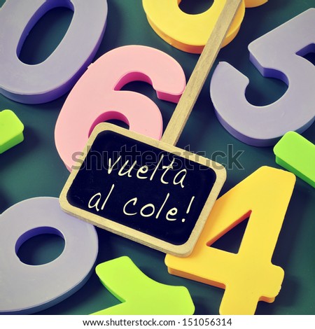 sentence vuelta al cole, back to school in spanish, written in a blackboard label and a pile of numbers of different colors in the background